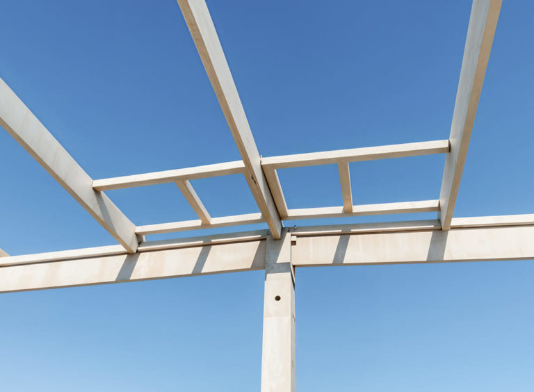 Vue en contre-plongée d’une charpente préfabriquée en béton installée sur un bâtiment en cours de construction