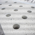 Détail des percements circulaires sur la surface de coursives en béton avec finition polie