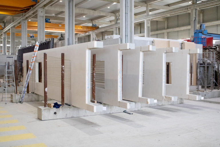 Vue d'ensemble de murs pleins en béton préfabriqué alignés dans l’usine CIR PREFA