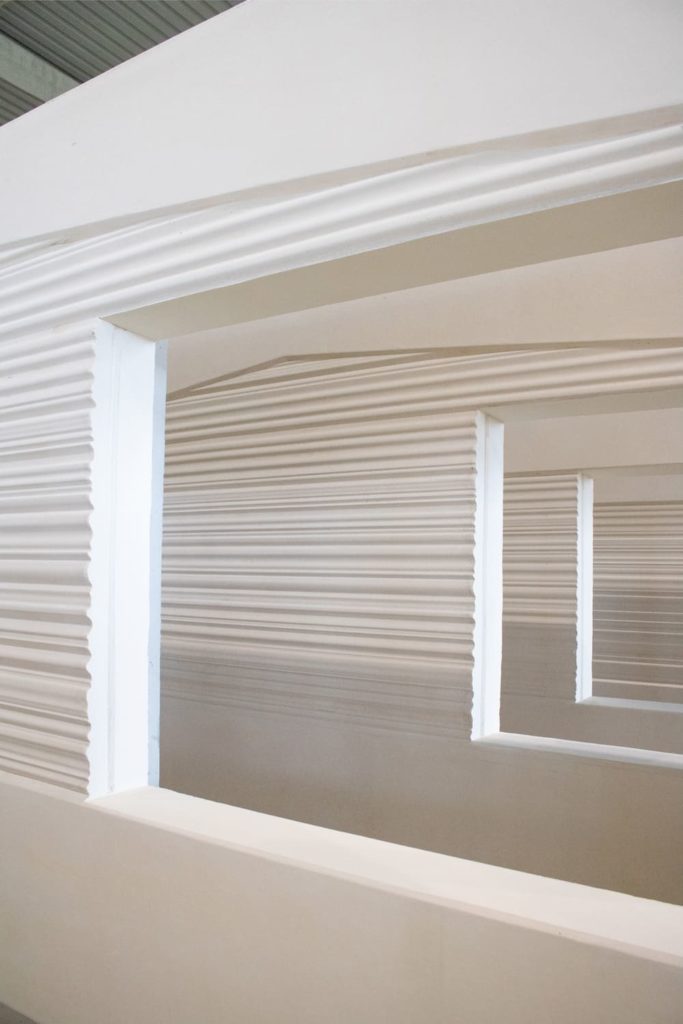 Zoom sur une ouverture encadrée dans un mur plein à texture striée